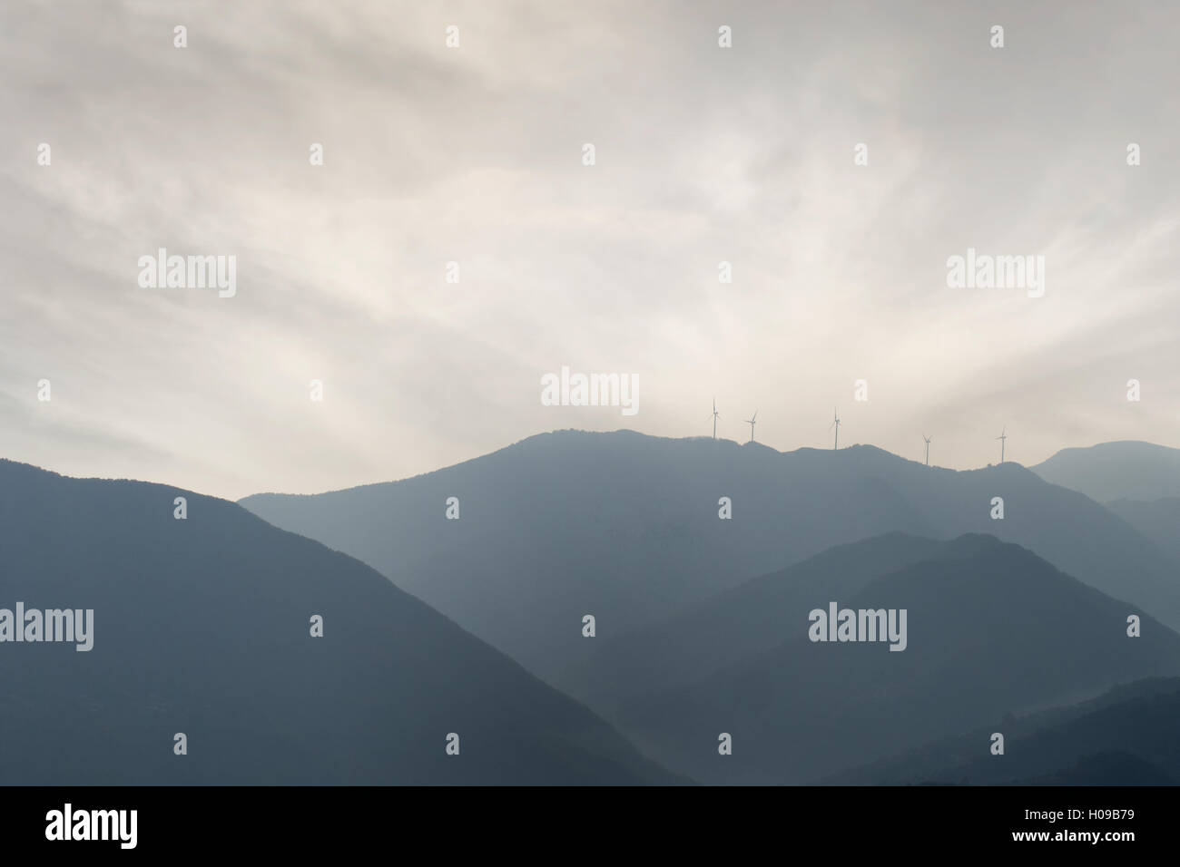 Atmospheric view of hills with wind turbines. Stock Photo