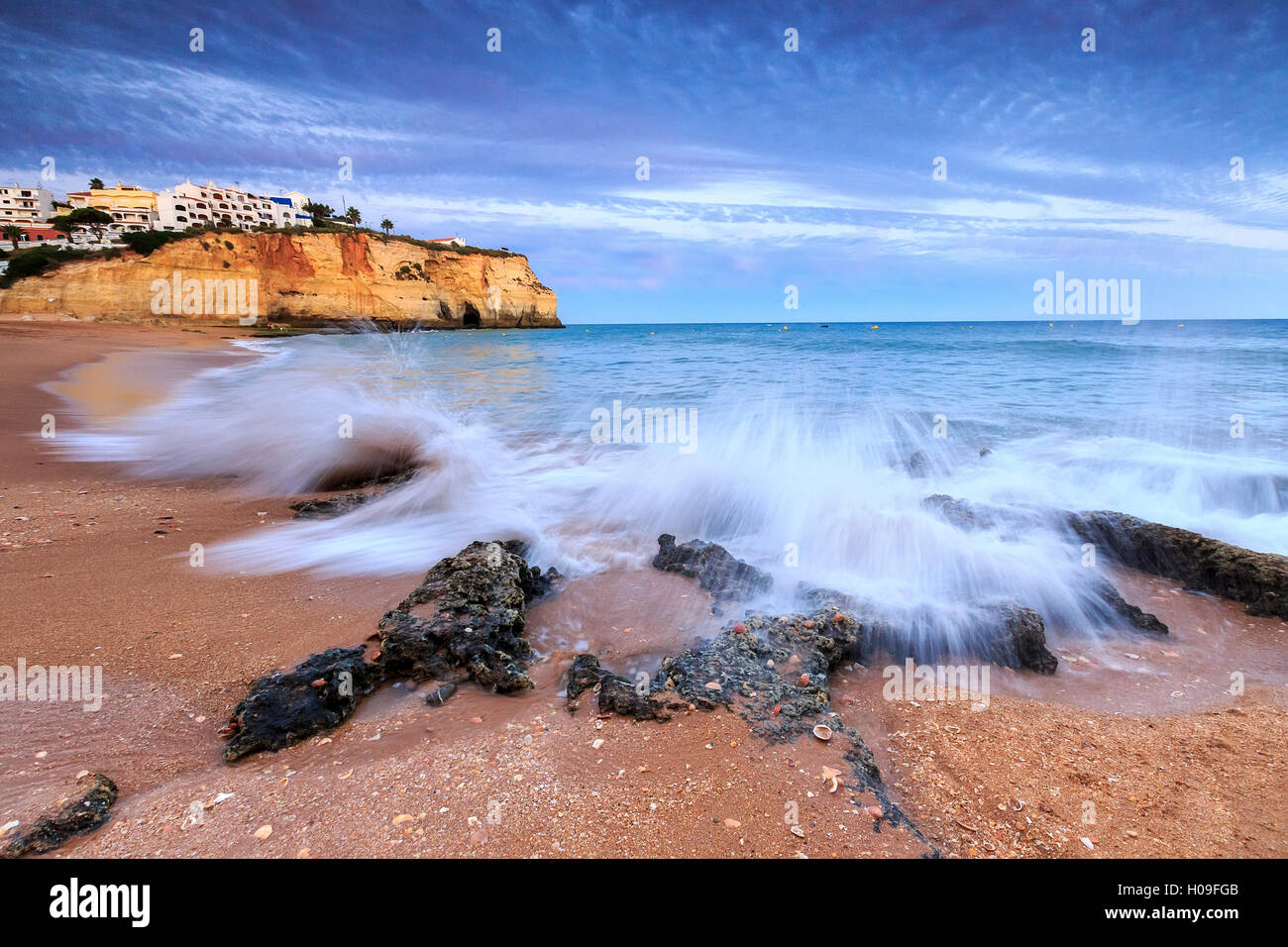 Ocean waves crashing on rocks and beach surrounding Carvoeiro village at sunset, Lagoa Municipality, Algarve, Portugal, Europe Stock Photo