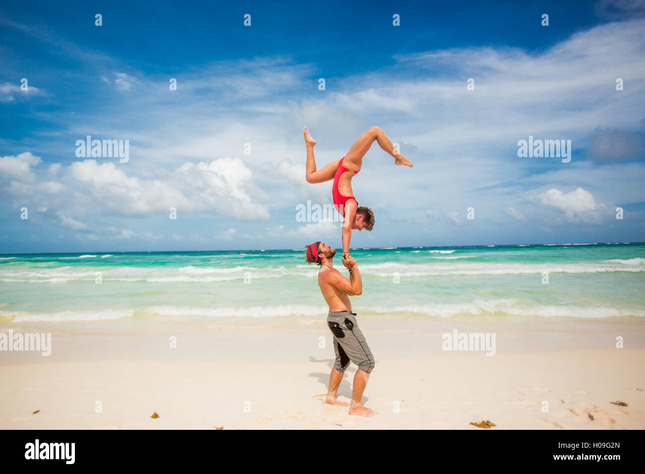 Acrobatic couple balancing together on the beach of Tulum, Mexico, North America Stock Photo