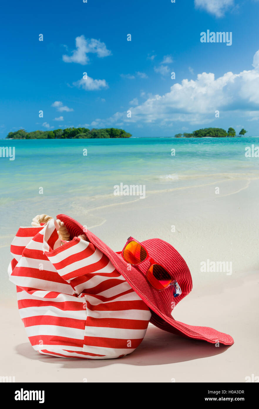 Summer beach bag with red  straw hat and sunglasses on sandy beach Stock Photo
