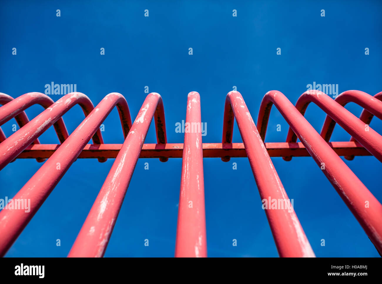 Red metal barred modern security barrier against a blue sky. Stock Photo