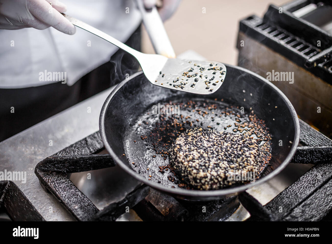 Red tuna steak crusted with white and black sesame seeds fried in oil Stock Photo