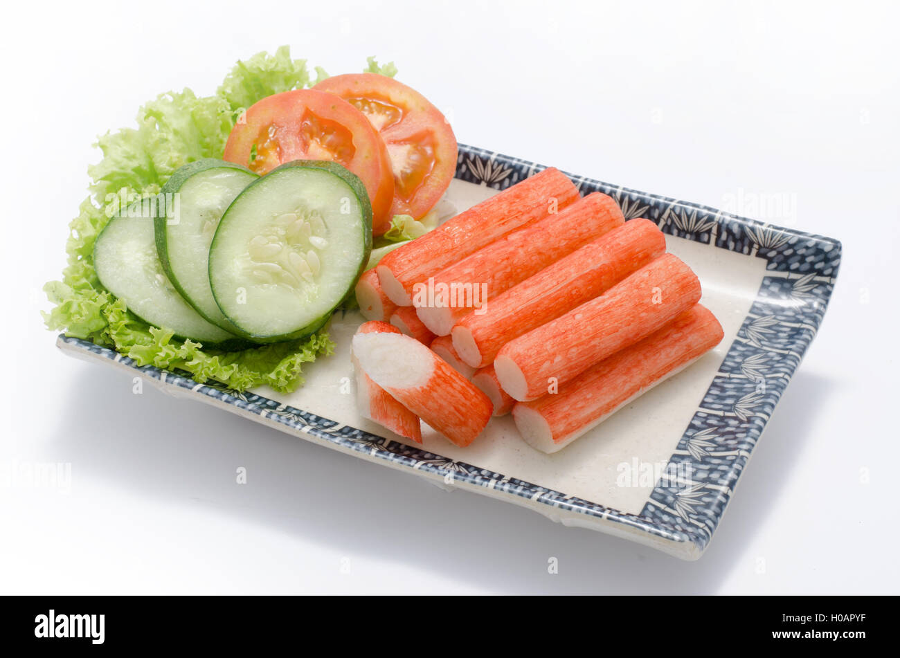 Crabmeat sticks with sliced cucumber and tomato on plate Stock Photo