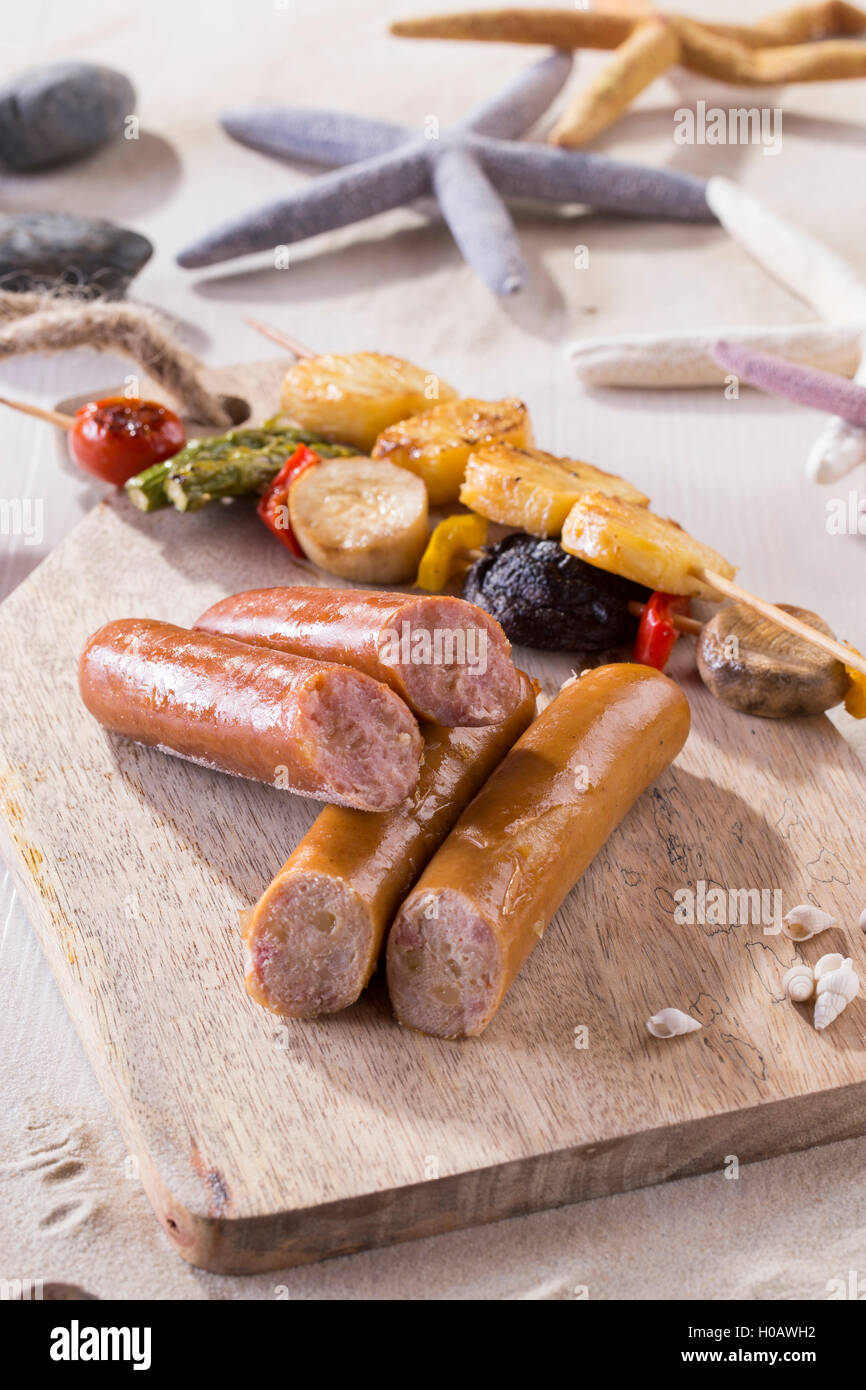 Saussages with scallop skewers on cutting board on the beach Stock Photo