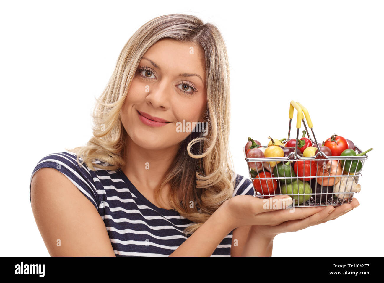 Joyful woman holding a small shopping basket full of vegetables and ...