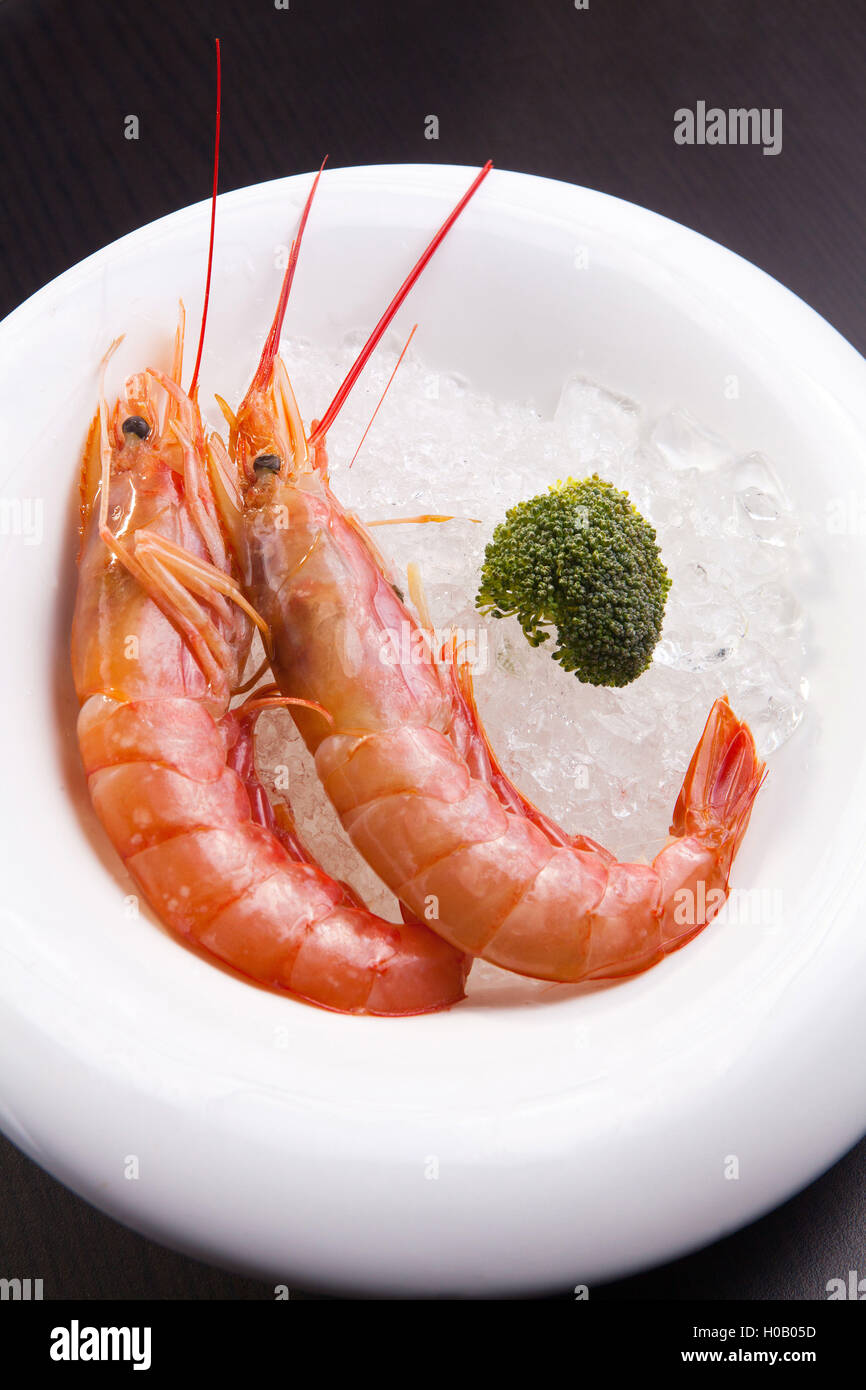 Steamed shrimps on ice on white plate with broccoli Stock Photo