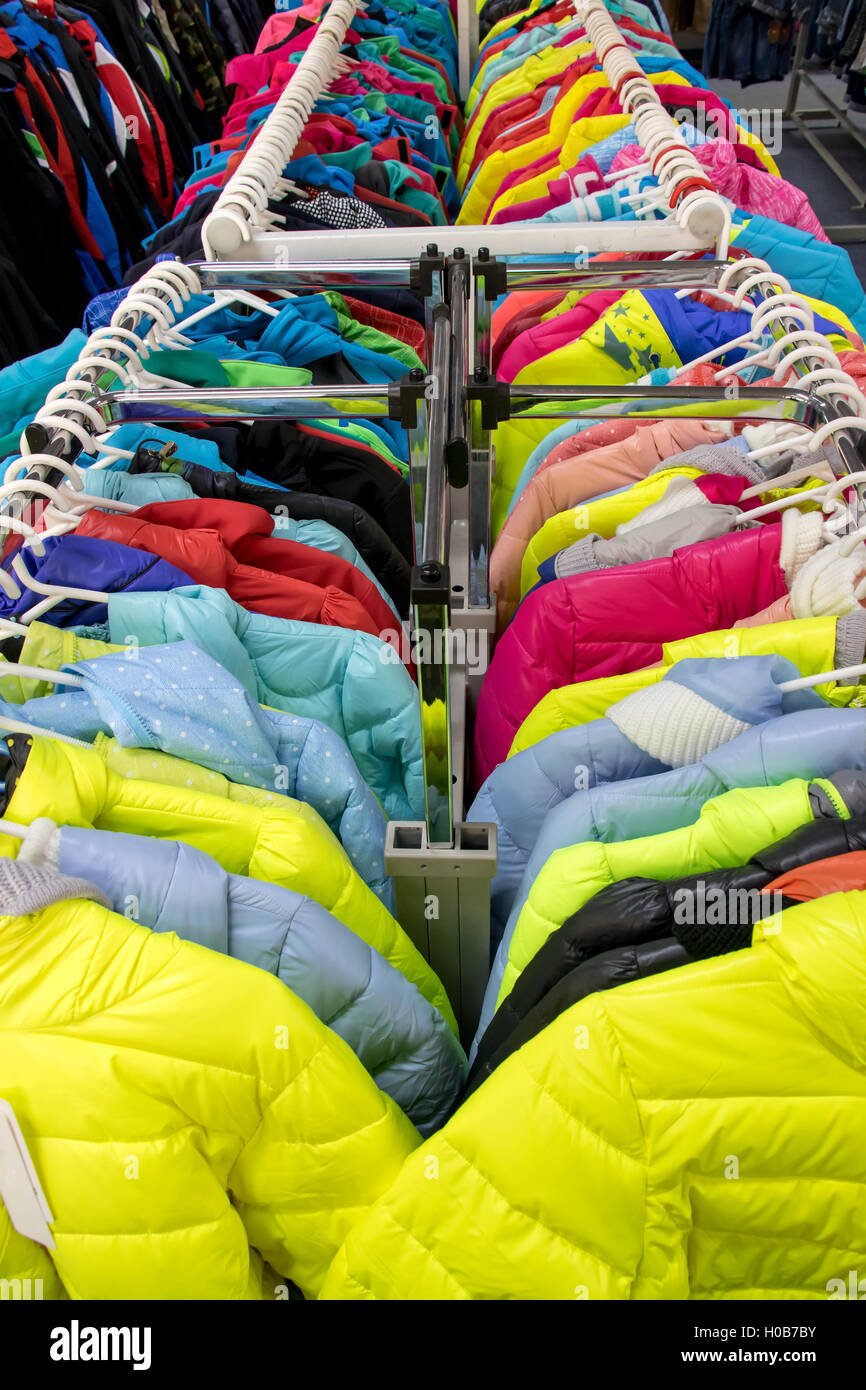 Variety of winter clothes on metal hangers. Colorful winter jackets