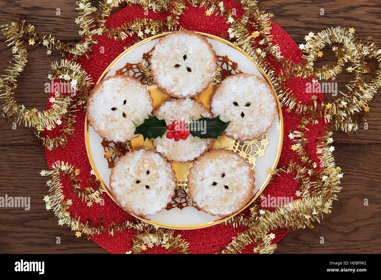 Christmas mince pie cakes with holly on a doilie and white plate with ...