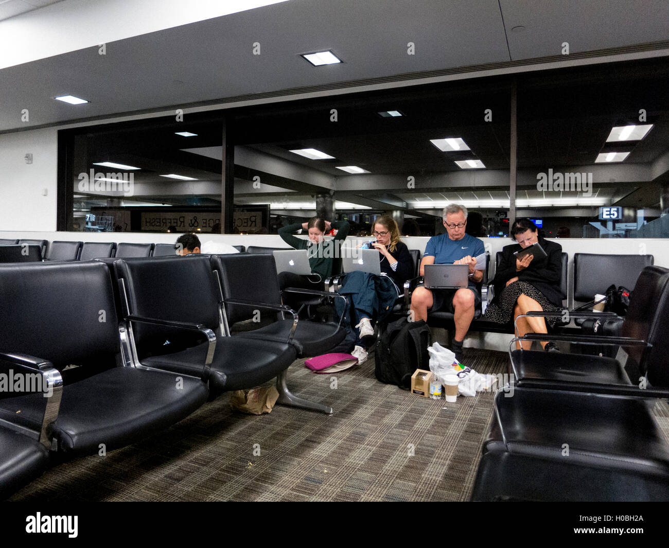 Passengers at Fort Lauderdale Hollywood airport busy with laptops while waiting. Stock Photo