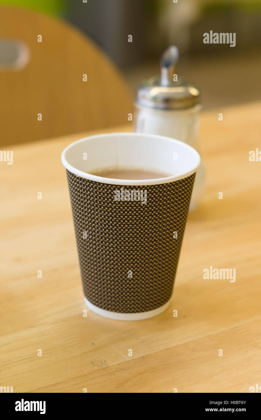 Disposable paper cup filled with tea on a table served in a cafe Stock Photo