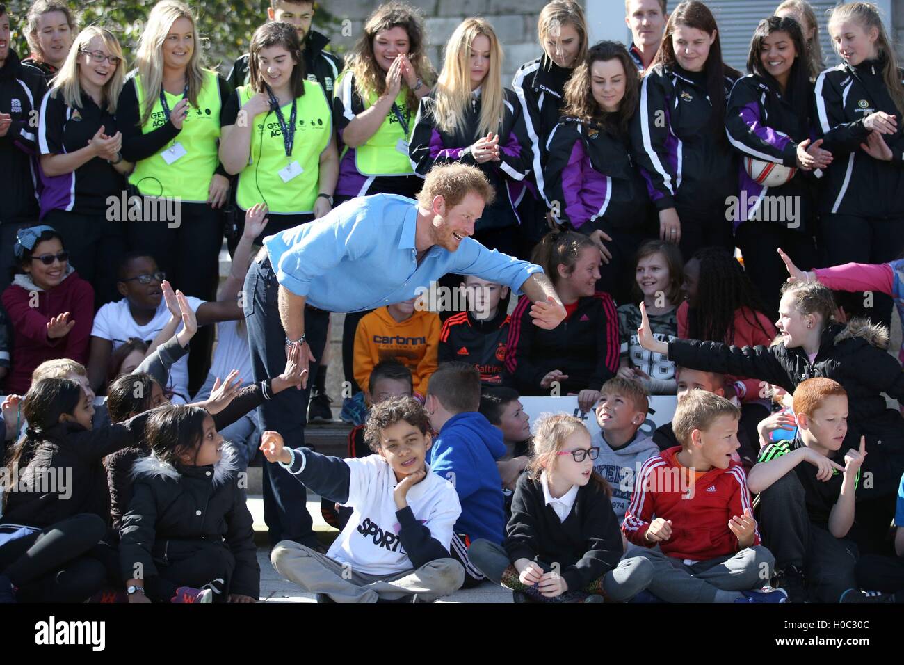 Prince Harry high-fives a pupil from Kaimhill School as volunteers from the Streetsport charity look on during a visit to Robert Gordon University in Aberdeen. Stock Photo