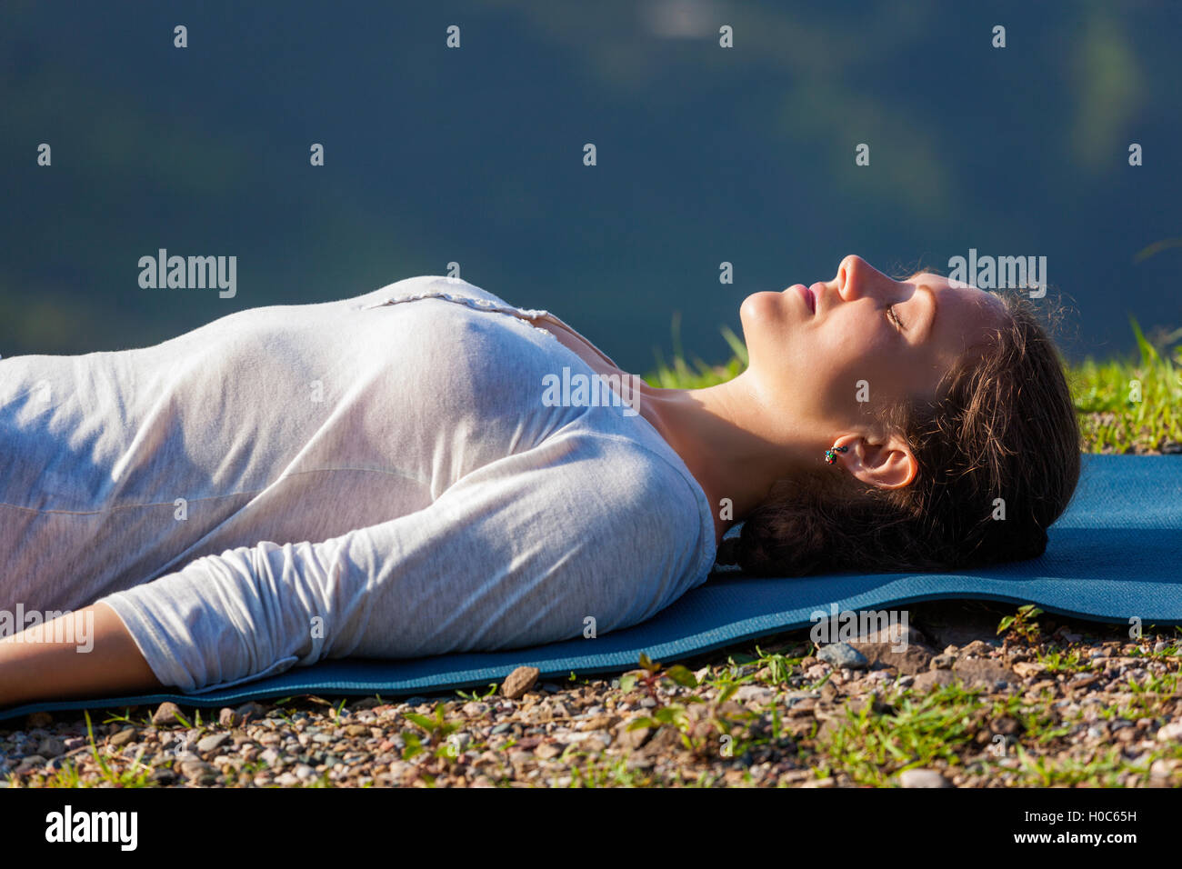 Woman relaxes in yoga asana Savasana outdoors Stock Photo