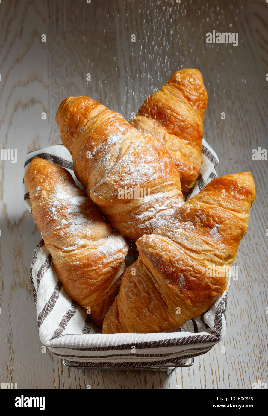 Tasty croissants in basket on wooden background Stock Photo