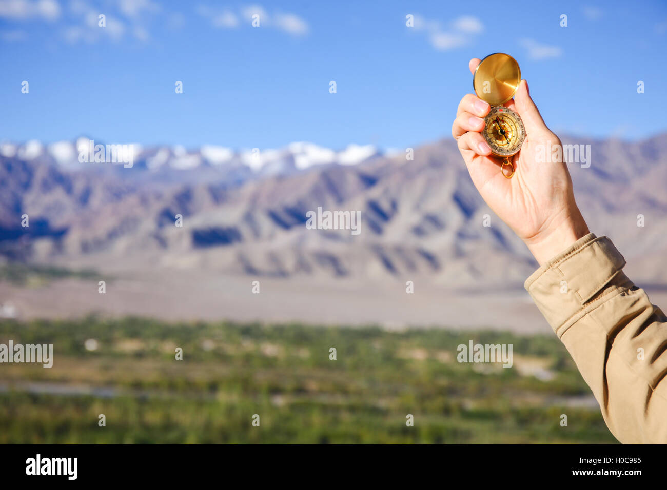 Young traveler looking at compass in Himalaya mountain view background (Focus on compass) Stock Photo