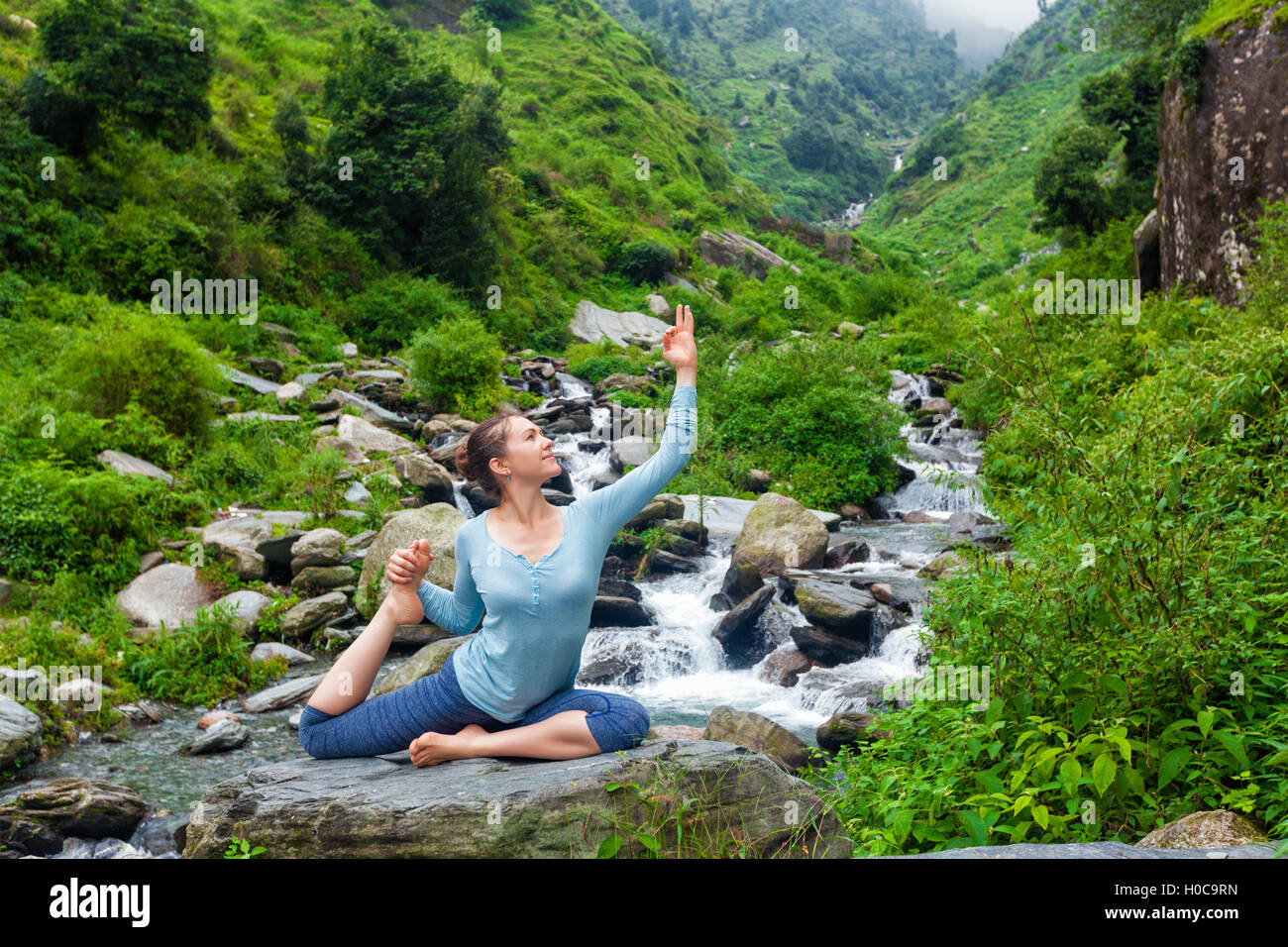 Sorty fit woman doing yoga asana outdoors at tropical waterfall Stock Photo