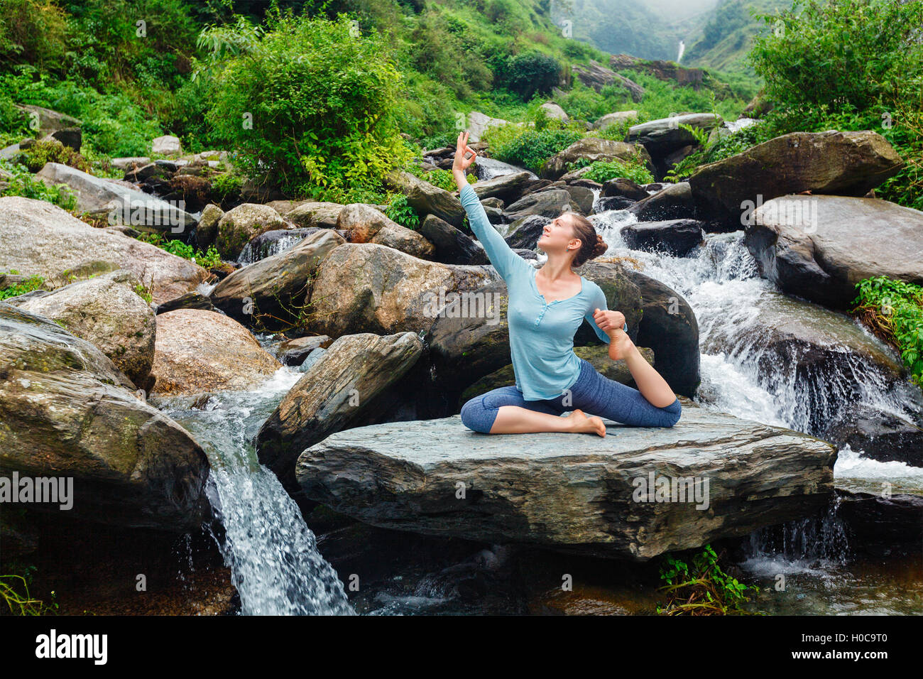Sorty fit woman doing yoga asana outdoors at tropical waterfall Stock Photo