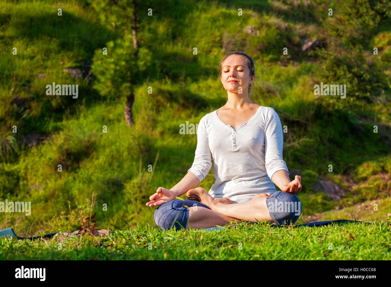 Young sporty fit woman doing yoga Lotus pose oudoors Stock Photo - Alamy
