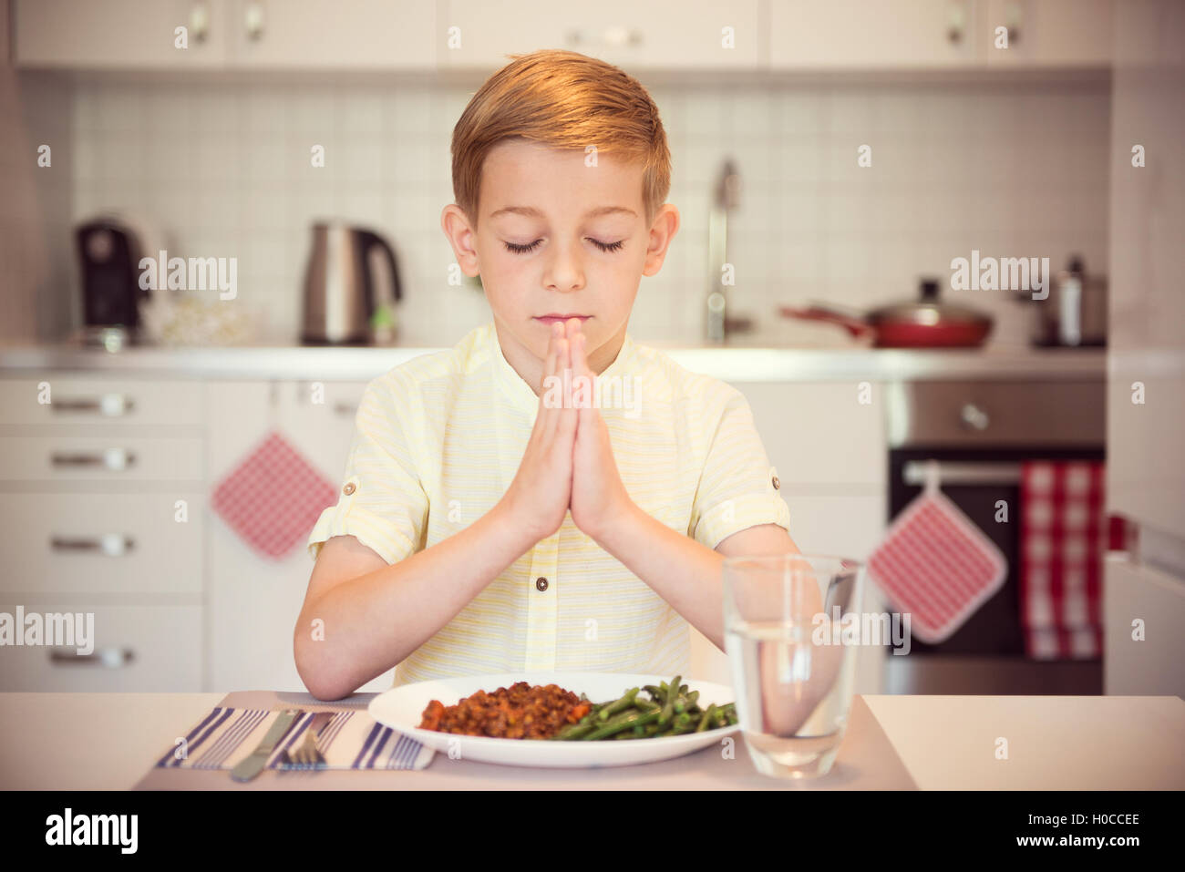 Cute little boy saying prayer before eating meal at home Stock Photo Alamy