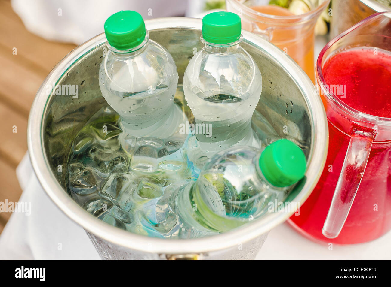 Bottled water in an ice bucket and a jug with juice Stock Photo Alamy