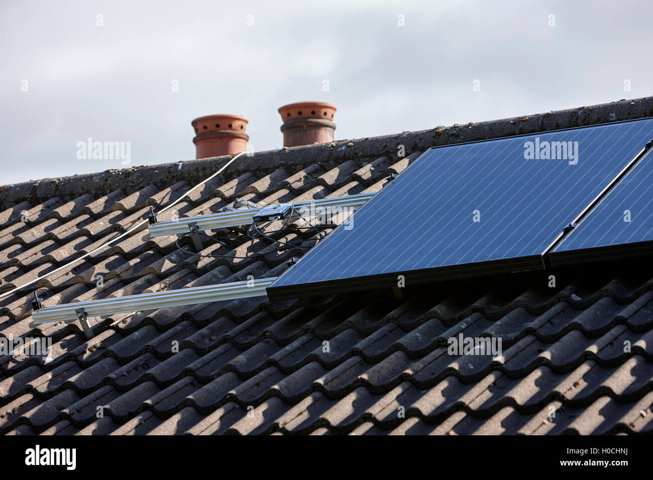 panels mounting rails and micro inverters in a domestic solar panel installation in the uk Stock Photo