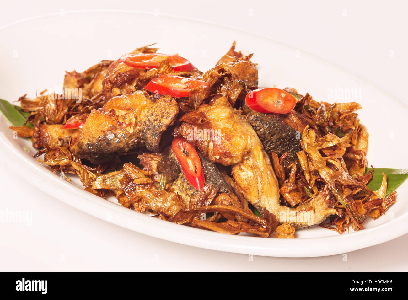 Fried frogs in Taiwanese style with chili and herbs on white plate Stock Photo