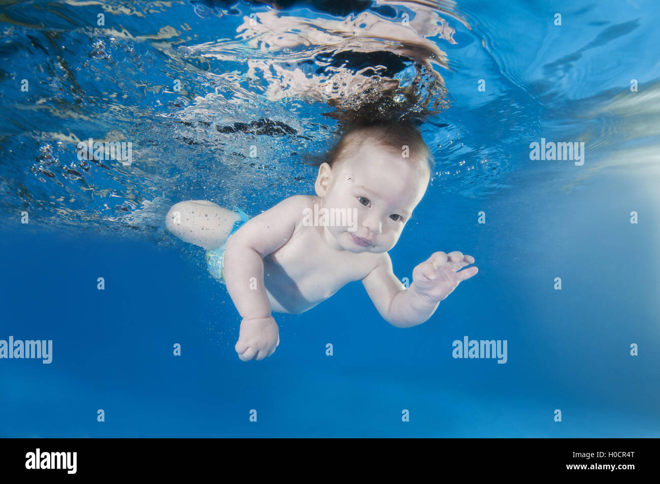 5 months infant boy learning to swim underwater in waterbaby class in