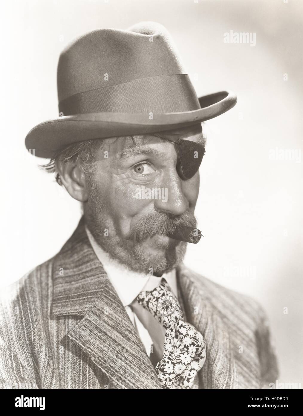 Man wearing eye patch and fedora smoking cigar Stock Photo