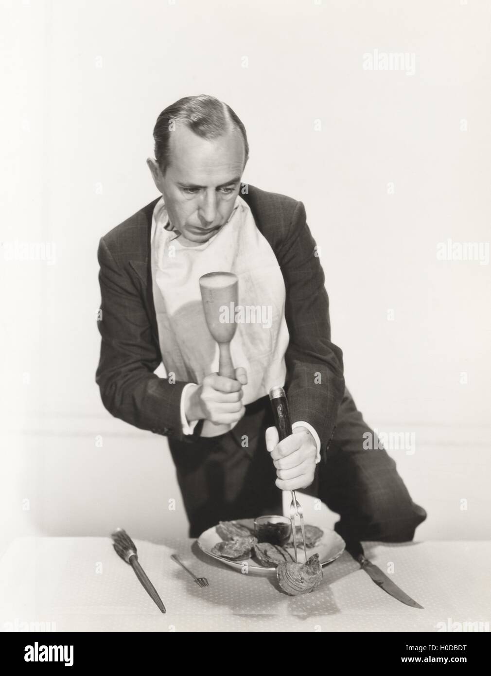 Man preparing to crack open oyster shell with mallet Stock Photo