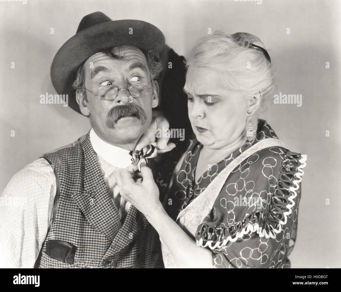 Woman straightening bewildered man's bow tie Stock Photo