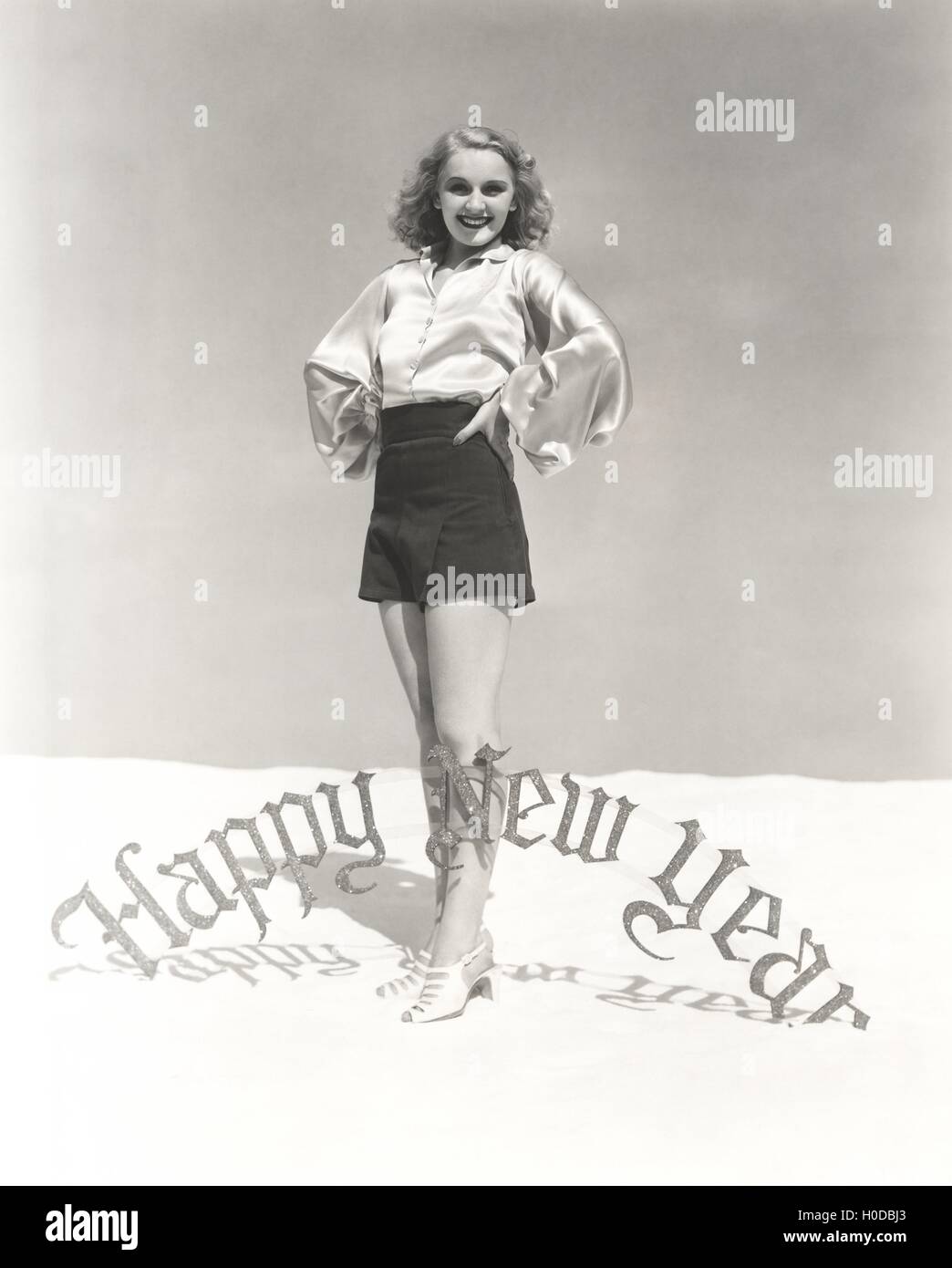 Portrait of smiling woman standing by Happy New Year sign Stock Photo ...