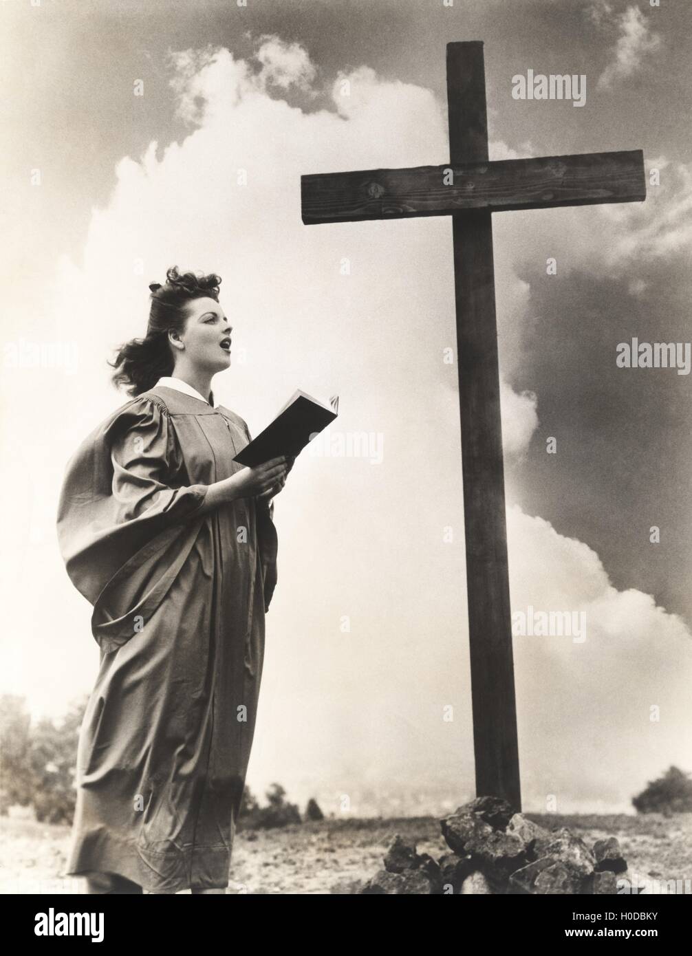 Woman singing hymns by a large wooden cross on a hill Stock Photo Alamy