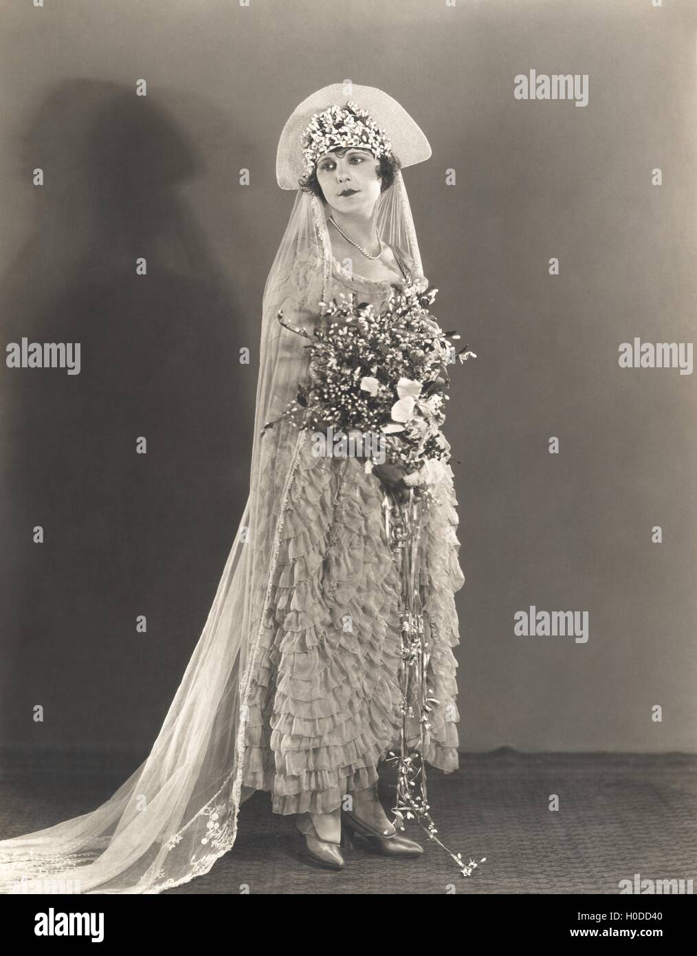 Bride wearing ruffled wedding gown and flowered headdress Stock Photo