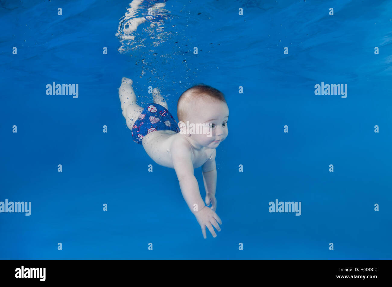 6 months infant boy learning to swim underwater in waterbaby class in
