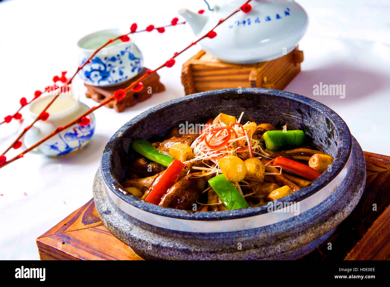 Freshwater eels braised with chili, vegetables and herbs in chinese stew with tea pot on wooden table Stock Photo