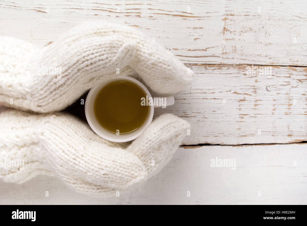 Woman's hands in gloves holding a cup of tea white wooden table Stock ...