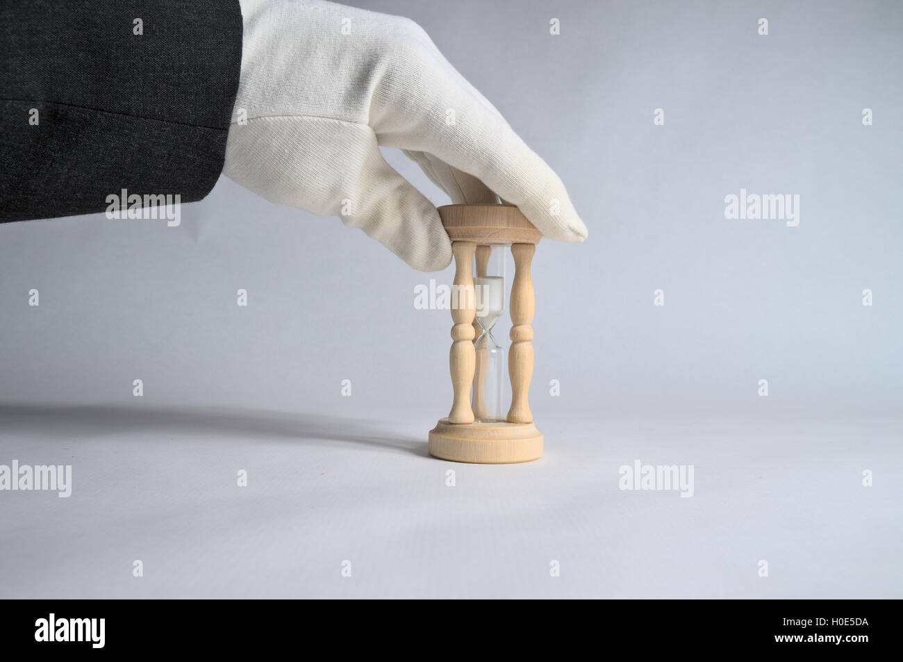 White glove touching an hourglass. Business and accommodation industry theme Stock Photo