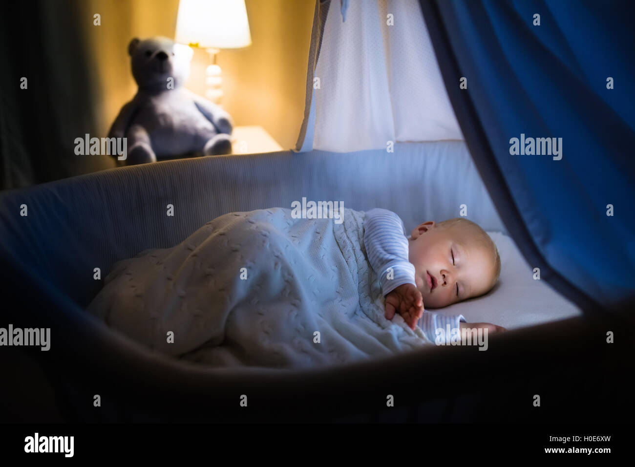 Adorable baby sleeping in blue with canopy at night. Little
