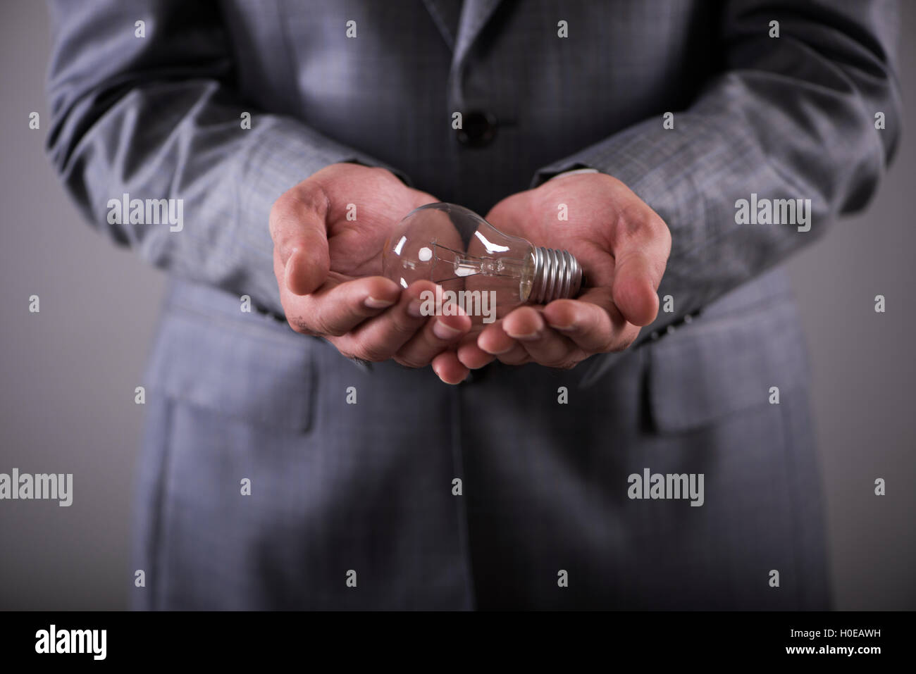 Businessman holding light bulb in creativity concept Stock Photo - Alamy