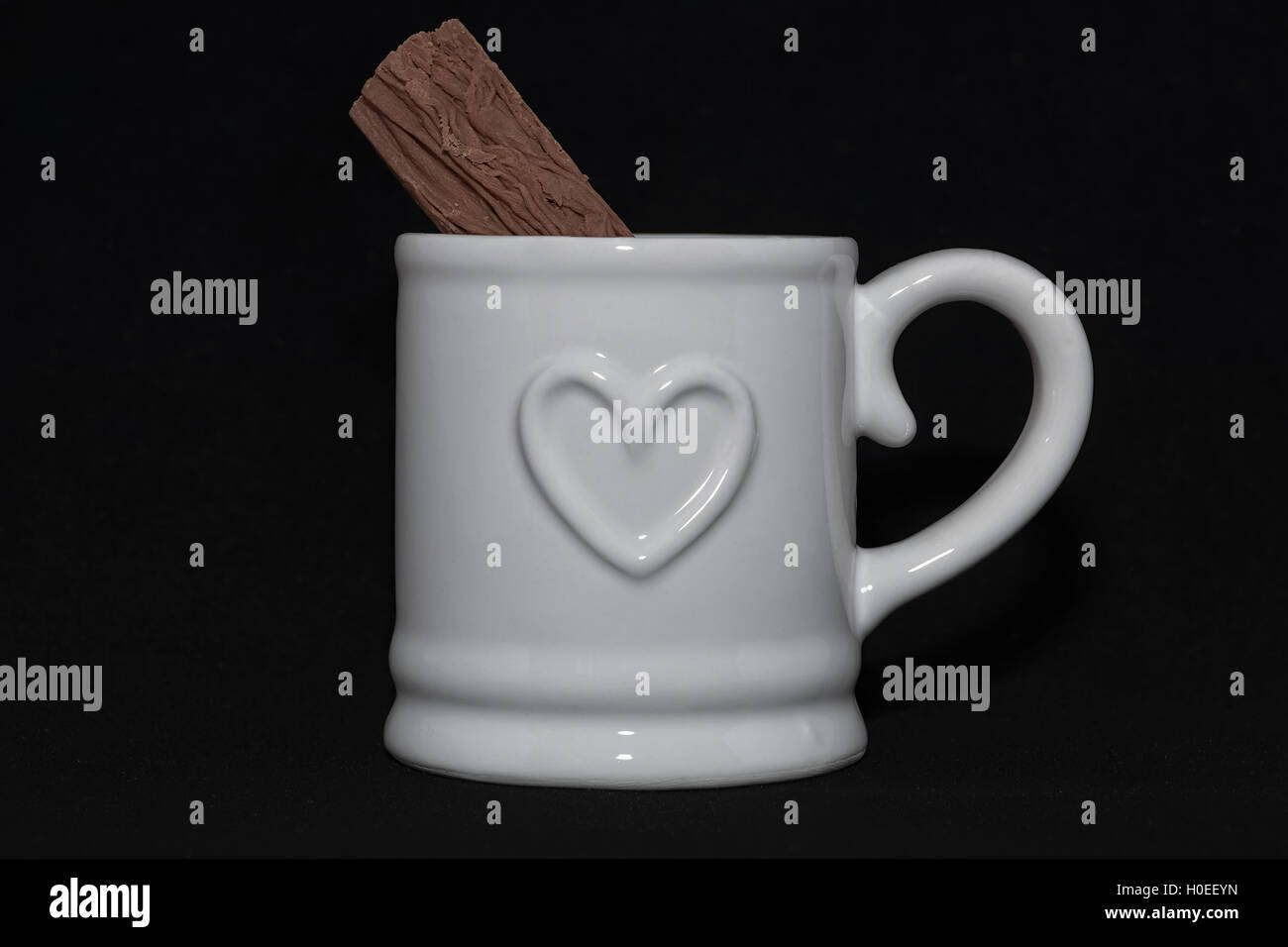 white mug with chocolate flake bar on black background Stock Photo