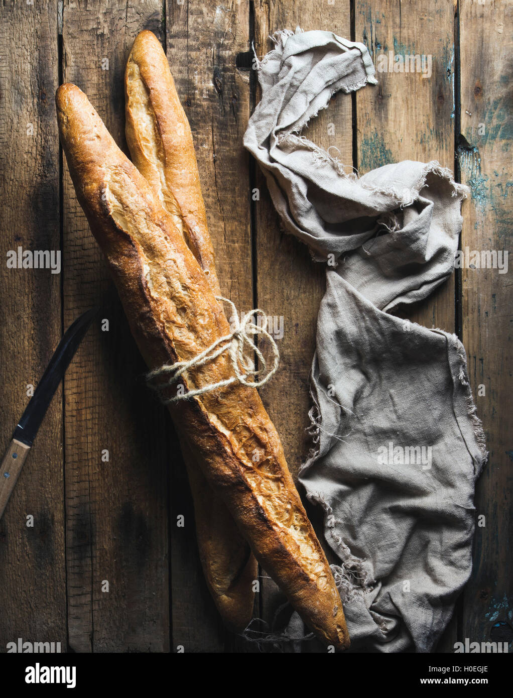 Two French baguettes on rough rustic wooden background. Top view, vertical composition Stock Photo