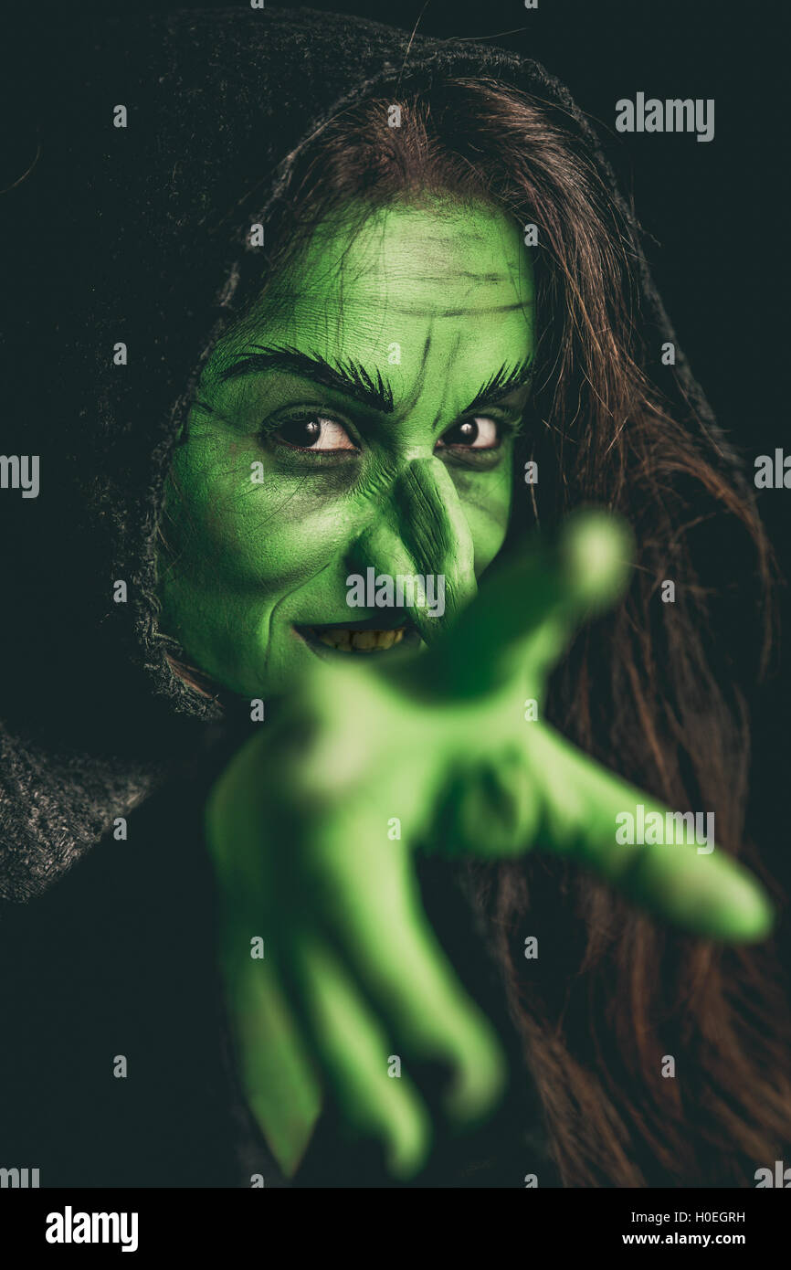 Green witch acting like she is casting a curse. Shallow depth of field. Stock Photo