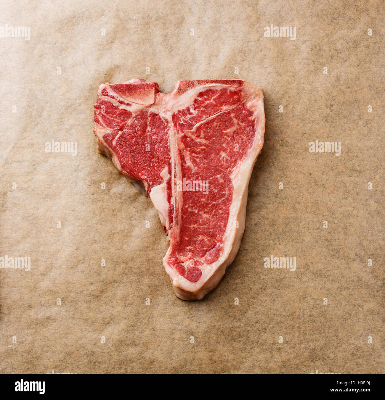 Raw fresh meat T-bone steak on cooking paper background Stock Photo