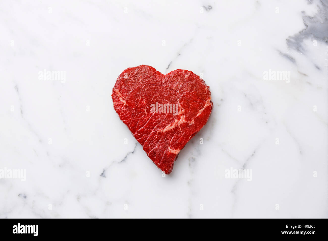 Heart shape Raw fresh meat on white marble background Stock Photo
