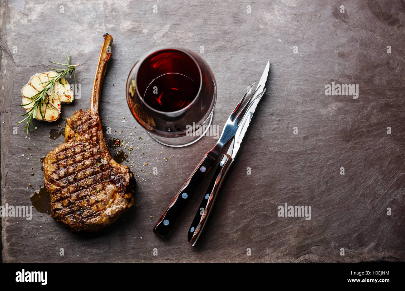 Grilled beef barbecue Veal rib Steak on bone and wine on stone slate background Stock Photo