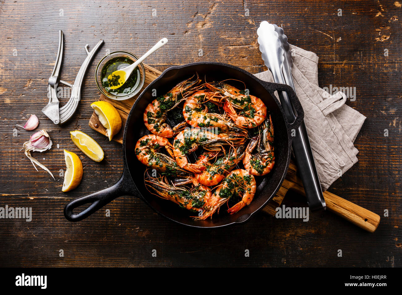 Tiger prawns shrimps roasted on frying grill pan with green sauce, lemon and garlic on wooden background Stock Photo