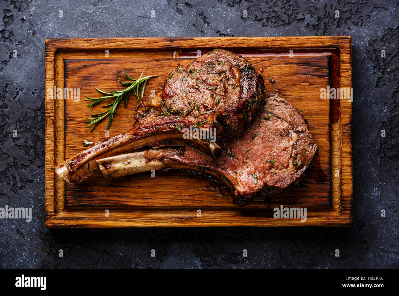 Roasted beef ribs on bone on wooden cutting board on dark background Stock Photo