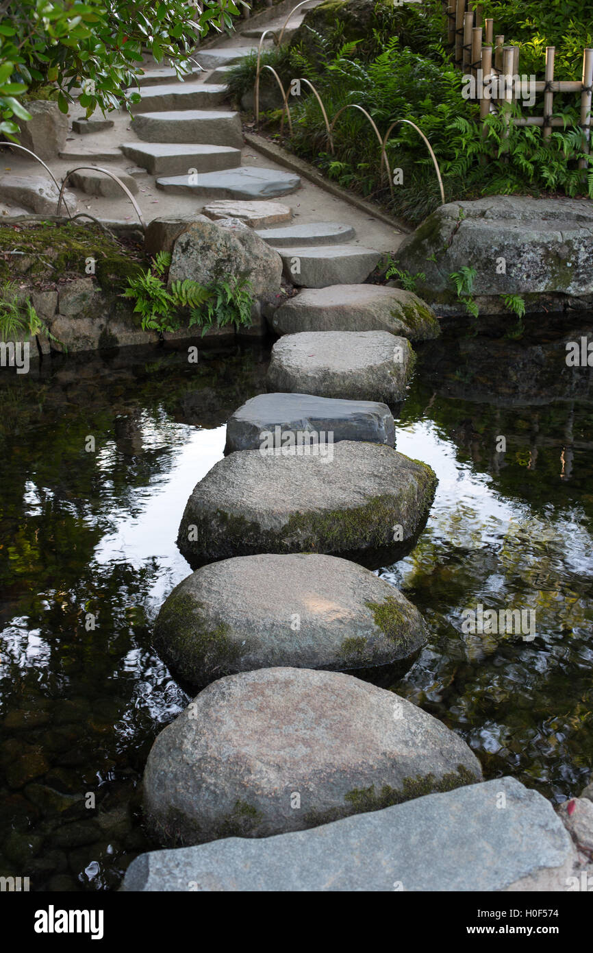 Zen stone path in a Japanese Garden across a tranquil pond in Okayama Stock Photo
