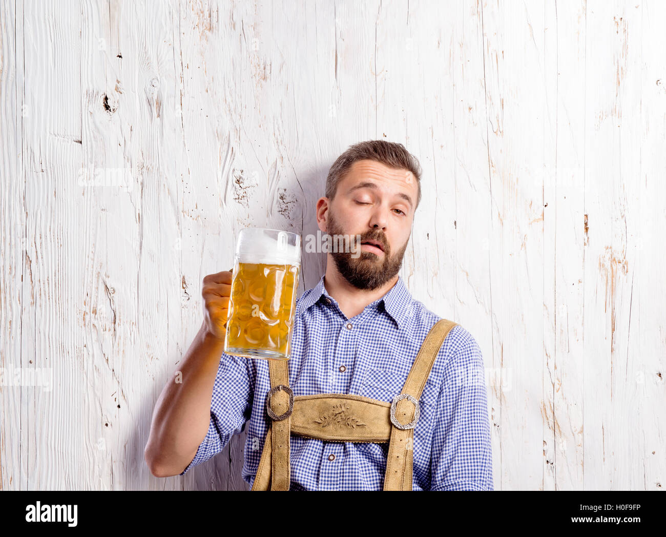 Drunk man in traditional bavarian clothes holding beer mugs Stock Photo