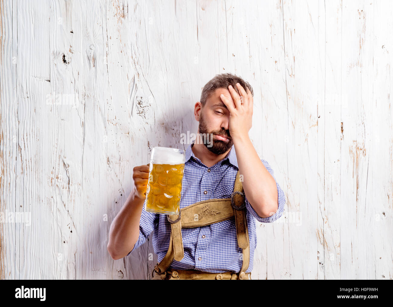 Drunk man in traditional bavarian clothes holding beer mugs Stock Photo