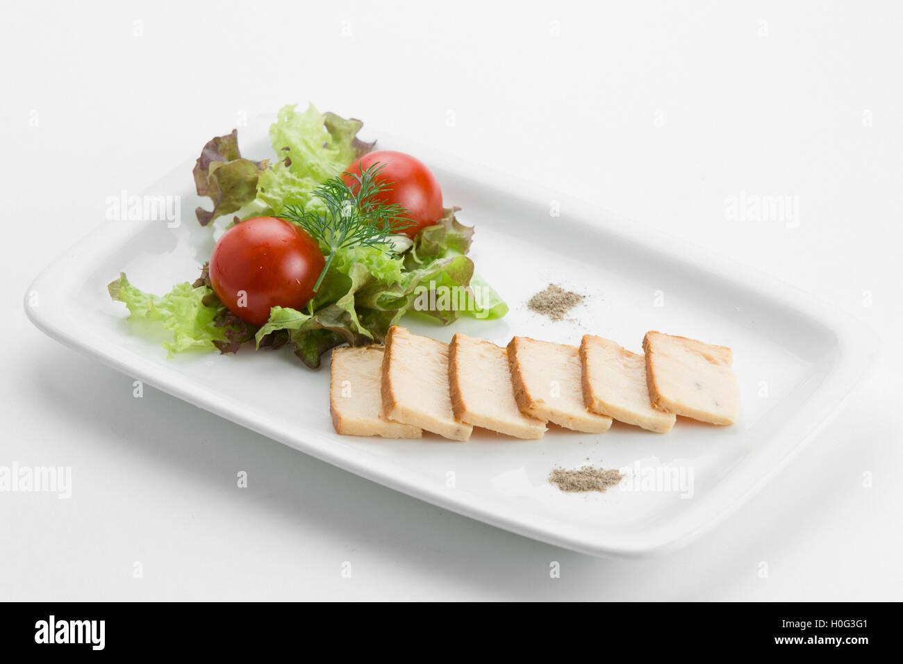 Oily fish smoked with mixed salad lettuce and tomatoes on white plate Stock Photo
